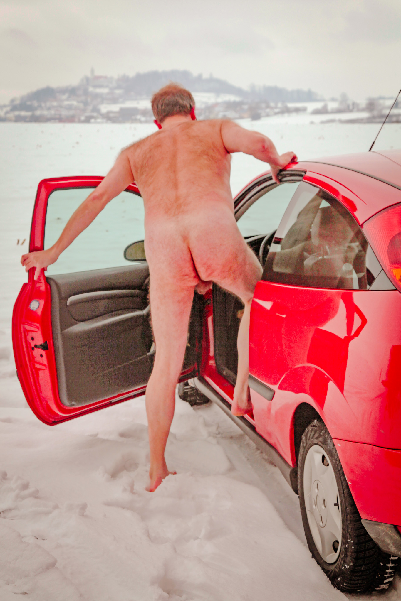 Stark naked car driver in the snow showing his bum in Germany